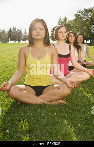 Quatre femmes faisant du yoga dans un parc Banque D'Images