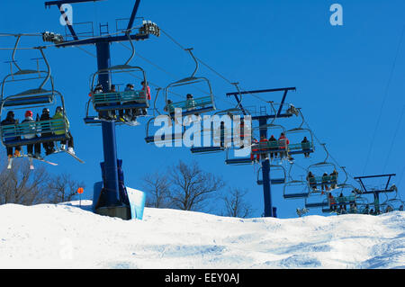 Skieurs sur un télésiège sur une pente de ski Banque D'Images