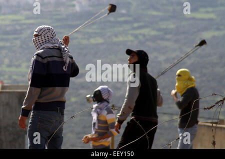 Kfar Qaddum, Cisjordanie, territoire palestinien. 23 Jan, 2015. Des manifestants palestiniens utiliser un lance-pierre à jeter des pierres vers les forces de sécurité israéliennes au cours d'affrontements à la suite d'une manifestation contre l'expropriation de terres palestiniennes par Israël dans le village de Kfar Qaddum, près de Naplouse en Cisjordanie occupée, le 23 janvier 2015 Credit : Nedal Eshtayah/APA/Images/fil ZUMA Alamy Live News Banque D'Images