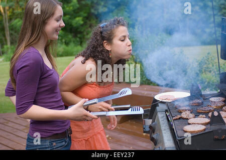 Deux jeunes femmes cuire des hamburgers Banque D'Images