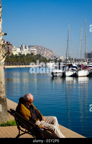 Le port d'Alicante et le port, l'Espagne, l'homme âgé dormir sur banc de la verticale à l'aide de château en arrière-plan Banque D'Images