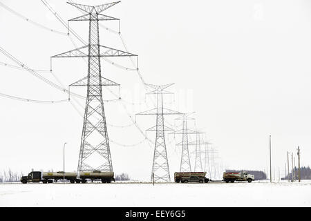 Une image horizontale de véhicules circulant sur une route rurale sous une ligne électrique Banque D'Images