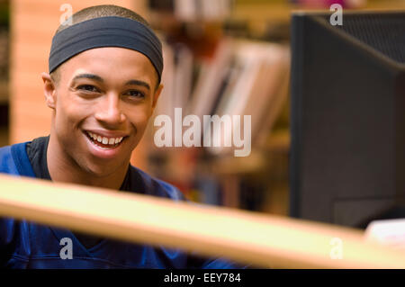 Jeune homme dans une bibliothèque à un terminal d'ordinateur Banque D'Images