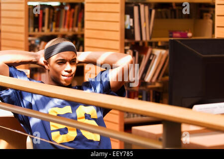 Jeune homme dans une bibliothèque à un terminal d'ordinateur Banque D'Images