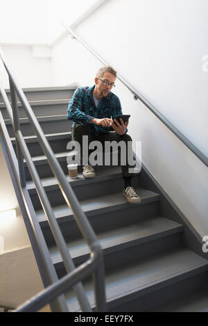 Homme assis sur les marches à l'aide de tablet pc Banque D'Images
