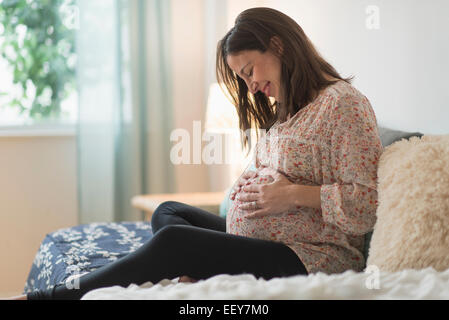 Pregnant woman sitting on bed Banque D'Images