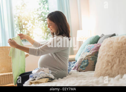 Pregnant woman watching baby clothing Banque D'Images