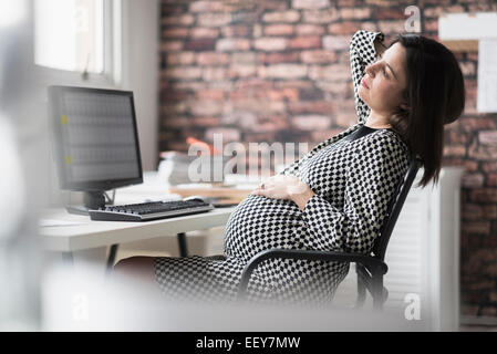 Pregnant woman relaxing in office Banque D'Images