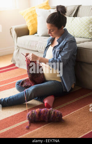 Pregnant woman sitting on floor knitting Banque D'Images