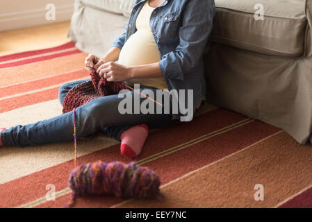 Pregnant woman sitting on floor knitting Banque D'Images