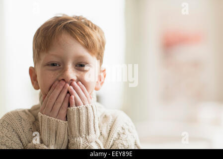 Portrait of boy (6-7) avec les mains couvrant la bouche Banque D'Images