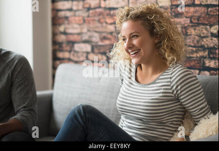 Blonde woman laughing on sofa Banque D'Images