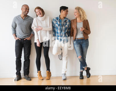 Laughing friends standing against white wall Banque D'Images