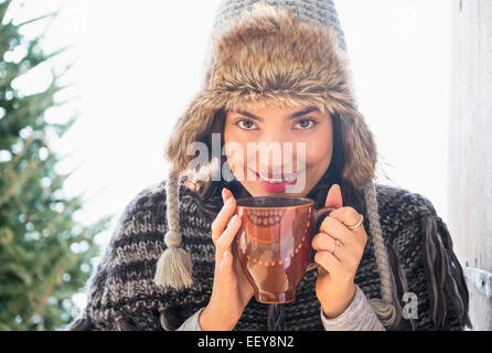 Portrait of young woman wearing winter hat, holding mug Banque D'Images