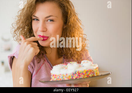 Jeune femme de gâteaux d'anniversaire dégustation Banque D'Images