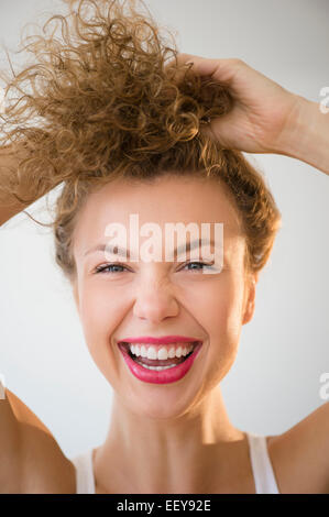 Jeune femme en riant et la tenue de cheveux Banque D'Images