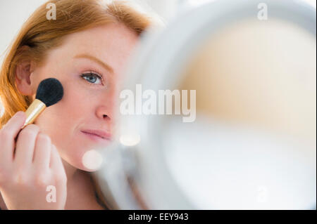 Young woman applying make up Banque D'Images