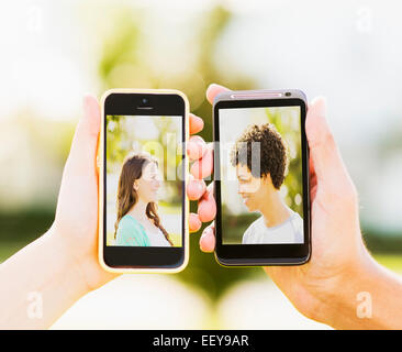 L'homme et teenage girl (14-15) holding téléphones intelligents avec des photos d'eux-mêmes Banque D'Images