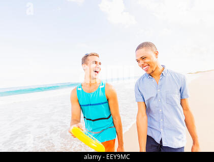 USA, Floride, Jupiter, jeune homme marchant et parlant, sur disque plastique holding beach Banque D'Images
