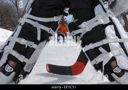 Les garçons jouer au hockey sur glace sur une patinoire extérieure Banque D'Images