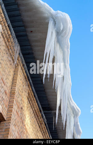 Gros glaçons pendant sur le toit de la maison au printemps Banque D'Images