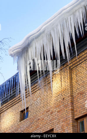 Gros glaçons pendant sur le toit de la maison au printemps Banque D'Images