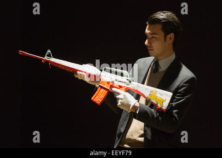 Londres, Royaume-Uni. 23 janvier 2015. Bonhams un employé détient l'œuvre 'Lion dans le Sable M-16", 2014 par Peter Doig. Le fusil d'assaut mis hors service est évalué à 5000-7000. Maison de ventes aux enchères Bonhams previews les éléments de la 'fondée' 1793 d'art contemporain qui aura lieu le 28 janvier 2015. La vente comprend une collection de 30 estampes Banksy, propriété de la galerie anglaise propriétaire, Steve Lazarides, et d'un ukulélé décoré par Damien Hurst. Photo : Bettina Strenske Banque D'Images