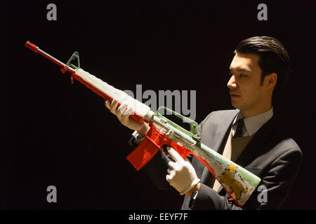 Londres, Royaume-Uni. 23 janvier 2015. Bonhams un employé détient l'œuvre 'Lion dans le Sable M-16", 2014 par Peter Doig. Le fusil d'assaut mis hors service est évalué à 5000-7000. Maison de ventes aux enchères Bonhams previews les éléments de la 'fondée' 1793 d'art contemporain qui aura lieu le 28 janvier 2015. La vente comprend une collection de 30 estampes Banksy, propriété de la galerie anglaise propriétaire, Steve Lazarides, et d'un ukulélé décoré par Damien Hurst. Photo : Bettina Strenske Banque D'Images