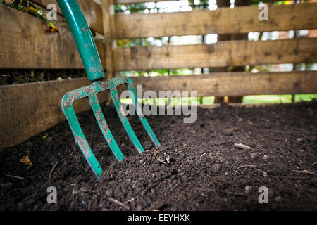 Tourner la fourche de jardin compostés dans le sol noir bac à compost en bois Banque D'Images