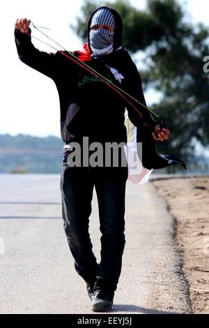 Un jeune Palestinien, avec le mot 'Palestine' écrite en arabe sur sa chemise est titulaire d'un home-made slingshot lors d'une démonstration hebdomadaire dans le village de Nabi Saleh. Vendredi hebdomadaire des manifestations contre l'occupation militaire et des colonies israéliennes illégales en Cisjordanie, en Palestine ont été arrêtés par des soldats israéliens et dispersées dans différentes villes. À Nabi Saleh, un petit village palestinien, situé au nord-ouest de Ramallah, les villageois et les activistes internationaux se sont réunis à mars du centre du village de leurs terres à travers la route. La marche a été stoppée par J Banque D'Images