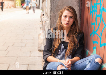 Jeune hipster girl sitting dans la rue. Banque D'Images