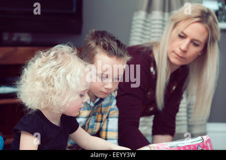 Petite fille présent avec ouverture du frère et de la mère Banque D'Images