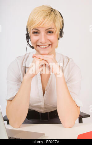 Blonde woman sitting at desk wearing headset Banque D'Images