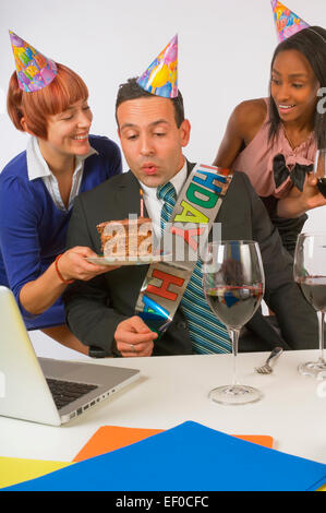 Woman blowing out bougie sur le gâteau d'anniversaire Banque D'Images