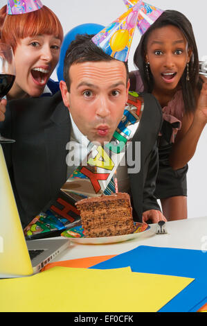 Woman blowing out bougie sur le gâteau d'anniversaire Banque D'Images