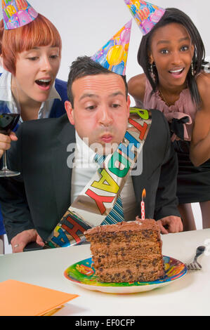 Woman blowing out bougie sur le gâteau d'anniversaire Banque D'Images