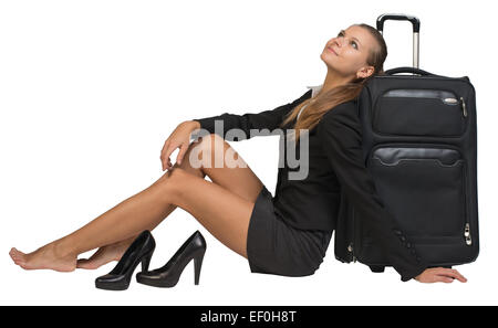 Businesswoman with her chaussures assis main reposant sur le sol, à côté d'valise vue avant Banque D'Images