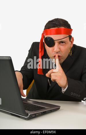 L'homme habillé en pirate typing on laptop Banque D'Images