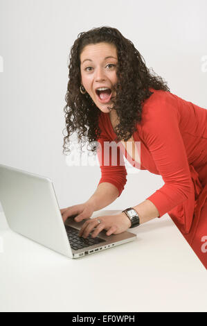 Excited woman typing on laptop Banque D'Images