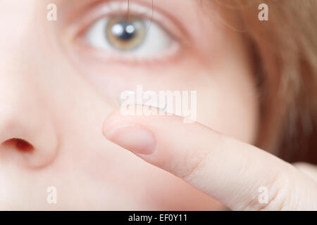 Des lentilles de contact des doigts près de woman's face close up Banque D'Images