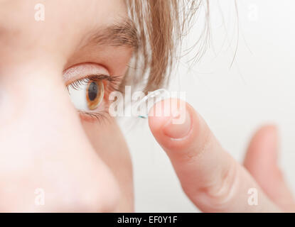 Jeune femme insère verre correcteur dans eye close up Banque D'Images