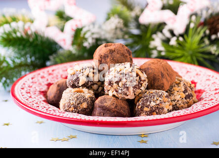 Truffes au chocolat noir assorties sur plaque rouge, décorations de fête, selective focus Banque D'Images