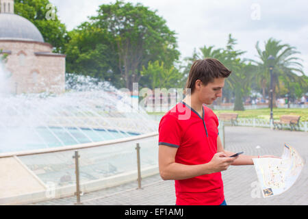 Portrait of young caucasian man with cellphone voyage et carte Banque D'Images