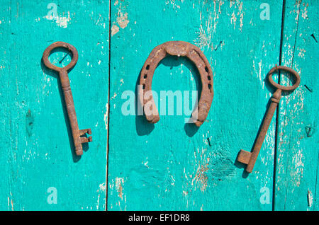 Deux meubles anciens clé historique rusty et symbole de chance à cheval sur un mur de ferme en bois Banque D'Images