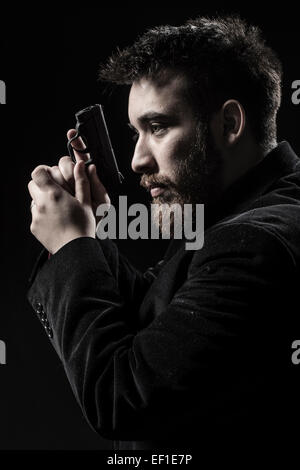 Jeune homme à la barbiche gauche face à des armes à feu Banque D'Images