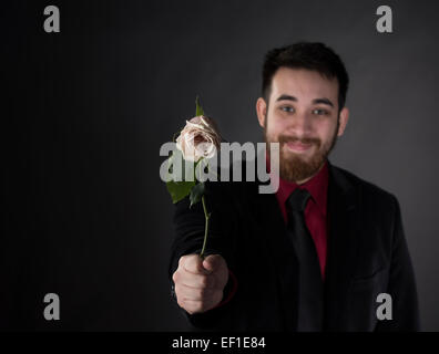 Homme heureux en costume officiel offrant une rose Banque D'Images