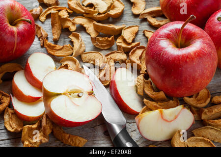 Des tranches de pommes séchées et fraîches de fruits rouges pomme rouge sur la vieille table de cuisine en bois Banque D'Images