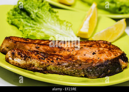 Saumon grillé avec des feuilles de salade fraîche et citron Banque D'Images