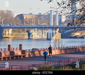 Les coureurs sur un matin d'hiver dans Battersea Park avec tamise et Chelsea Bridge en arrière-plan l'Europe Angleterre Londres Banque D'Images