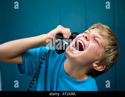 10,11,12,13 enfant rire tout en parlant au téléphone, récepteur holding Banque D'Images